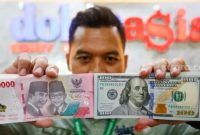 Petugas salah satu tempat penukaran mata uang asing menunjukkan uang rupiah dan dollar AS di Jakarta, Selasa (19/5/2026). [Suara.com/Alfian Winanto] 