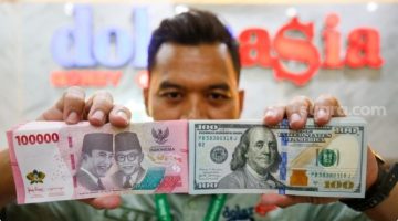 Petugas salah satu tempat penukaran mata uang asing menunjukkan uang rupiah dan dollar AS di Jakarta, Selasa (19/5/2026). [Suara.com/Alfian Winanto] 