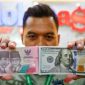 Petugas salah satu tempat penukaran mata uang asing menunjukkan uang rupiah dan dollar AS di Jakarta, Selasa (19/5/2026). [Suara.com/Alfian Winanto] 