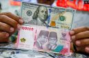 Petugas salah satu tempat penukaran mata uang asing menunjukkan uang rupiah dan dollar AS di Jakarta. [Suara.com/Alfian Winanto] 