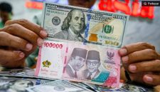 Petugas salah satu tempat penukaran mata uang asing menunjukkan uang rupiah dan dollar AS di Jakarta. [Suara.com/Alfian Winanto] 