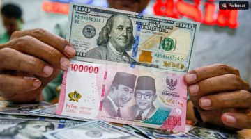 Petugas salah satu tempat penukaran mata uang asing menunjukkan uang rupiah dan dollar AS di Jakarta. [Suara.com/Alfian Winanto] 