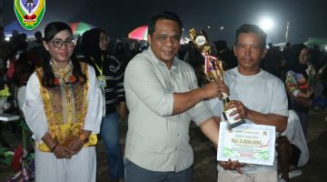 Wakil Ketua I DPRD Kabupaten Seruyan, Harsandi, menyerahkan tropy kepada salah satu pemenang lomba dalam kegiatan Danau Sembuluh Ethnic Festival (DSEF) 2026.