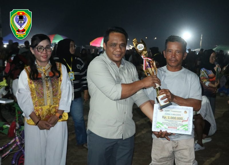 Wakil Ketua I DPRD Kabupaten Seruyan, Harsandi, menyerahkan tropy kepada salah satu pemenang lomba dalam kegiatan Danau Sembuluh Ethnic Festival (DSEF) 2026.
